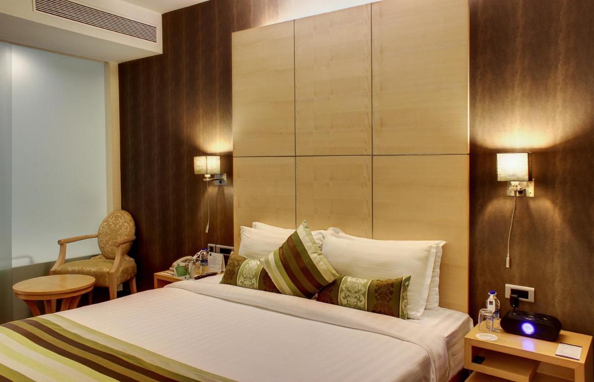 a hotel room with a bed and a chair at Novotel Hyderabad Airport in Hyderabad