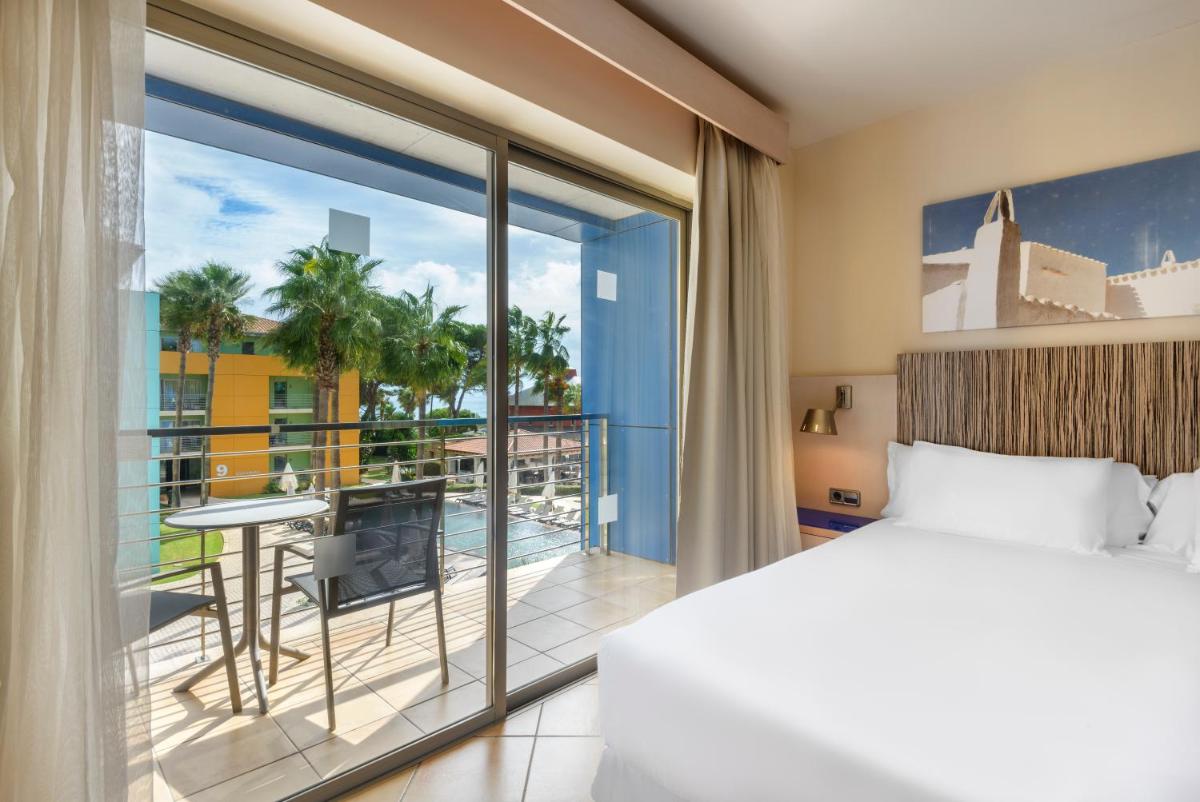 Un dormitorio con una cama y un balcón con vistas. en Occidental Menorca, en Punta Prima