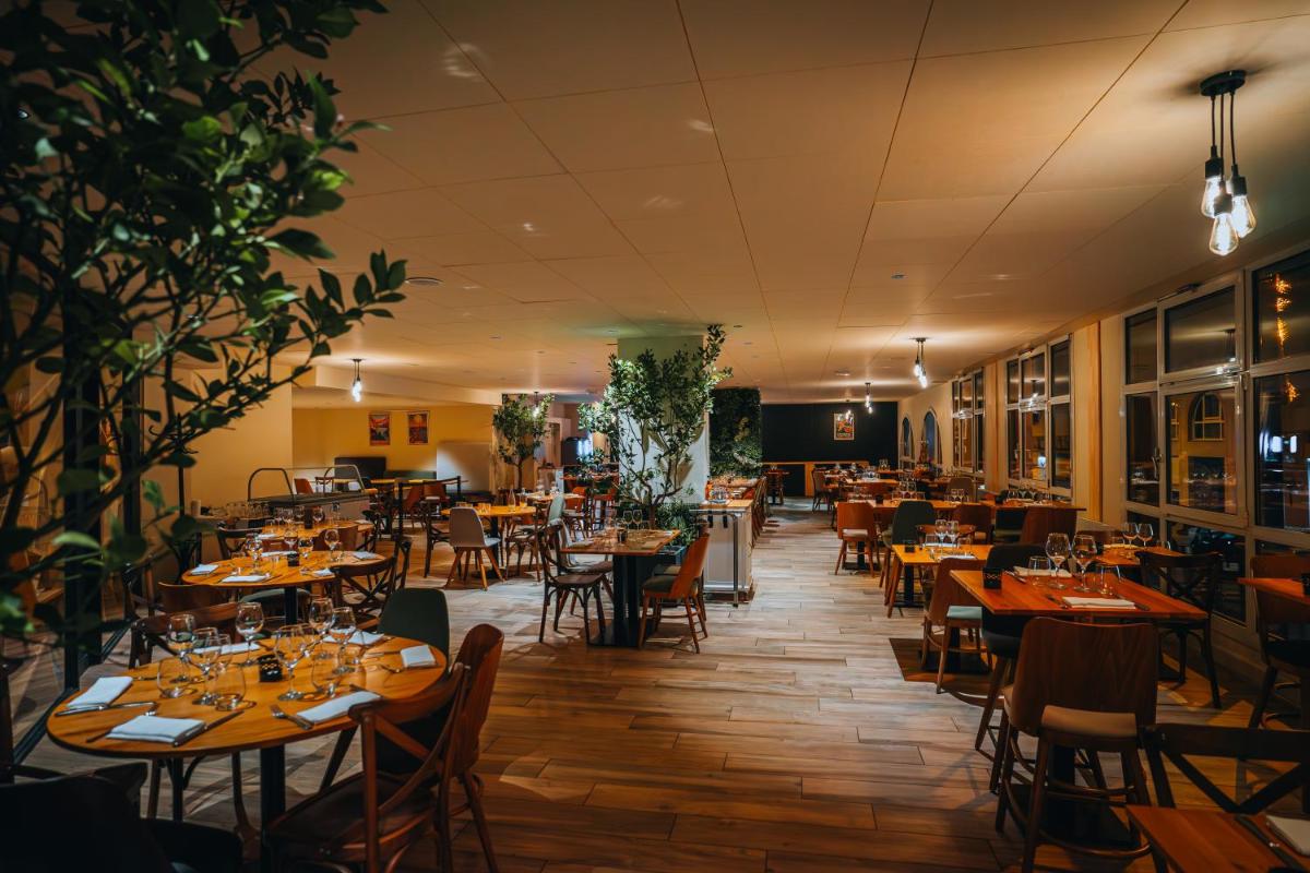 un restaurant avec des tables et des chaises en bois et un chercheur de table dans l'établissement Garden & City Cauterets Balneo, à Cauterets