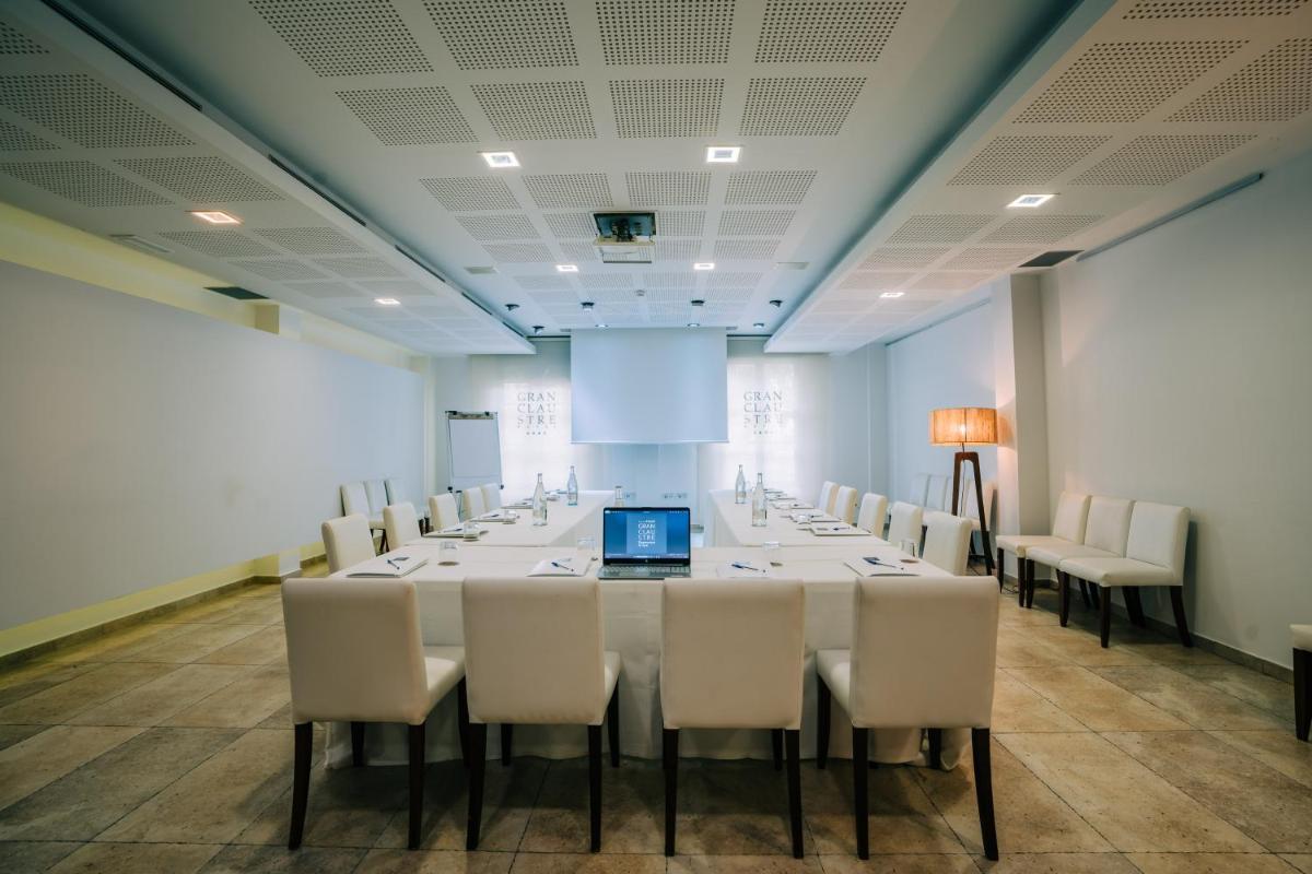 Una sala de conferencias con una mesa larga y sillas blancas. en Gran Claustre Boutique Hotel, en Altafulla