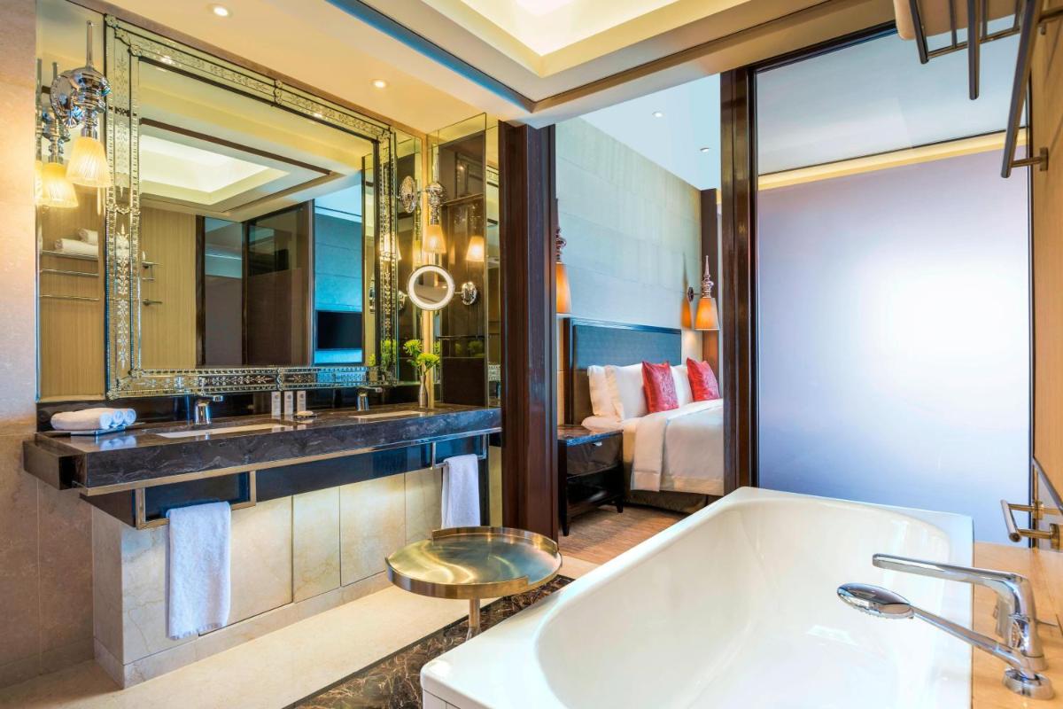 a bathroom with a tub and a mirror and a bed at The St. Regis Mumbai in Mumbai