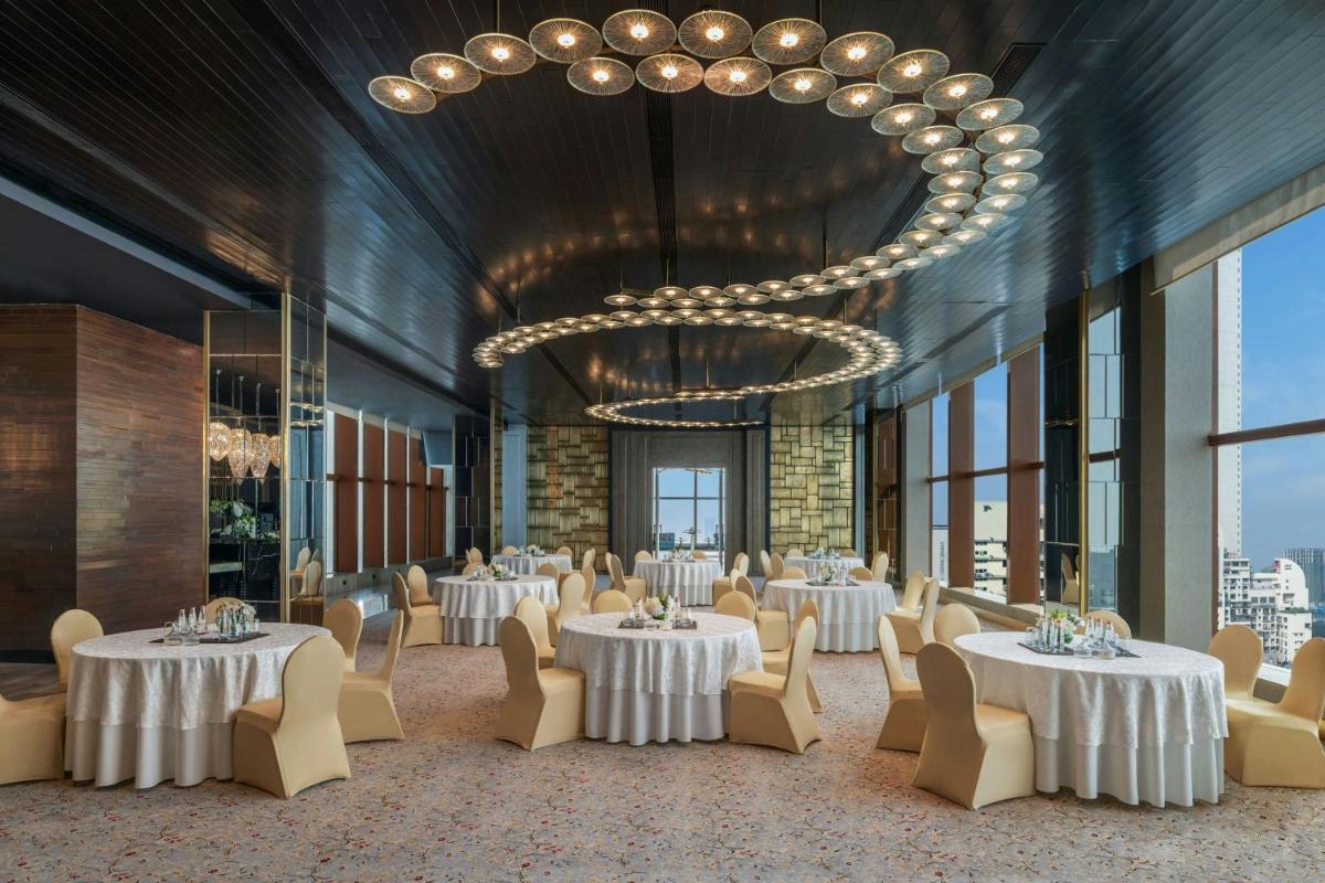 a dining room with tables and chairs and a chandelier at The St. Regis Mumbai in Mumbai