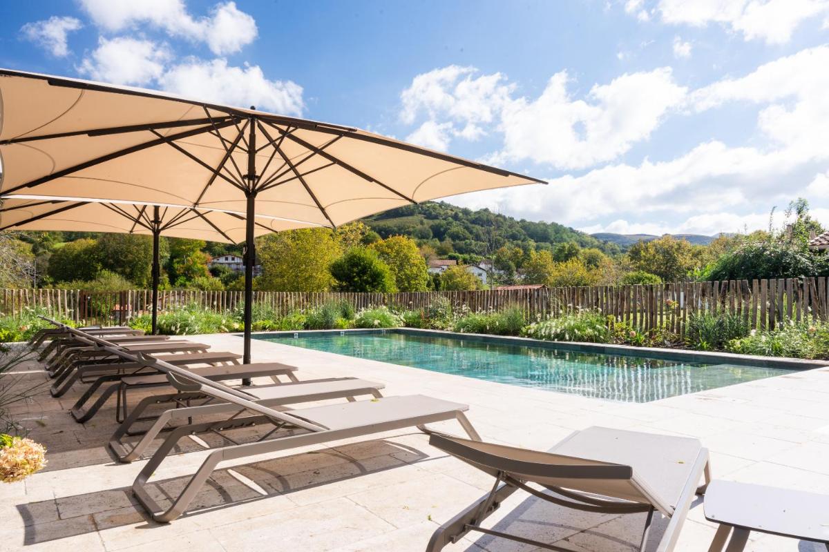 - un groupe de chaises longues et de parasols à côté de la piscine dans l'établissement Hôtel Restaurant & Spa La Maison Oppoca, à Ainhoa