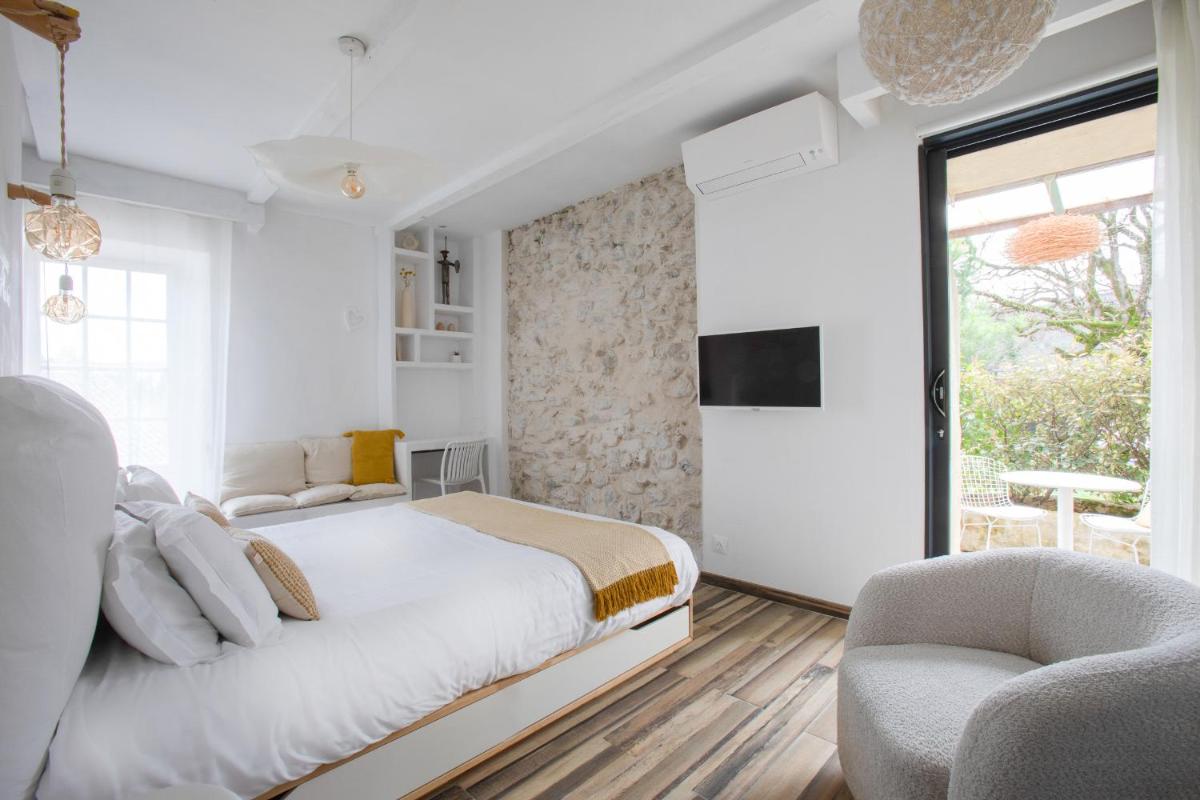 une chambre blanche avec un grand lit et deux chaises dans l'établissement DODO etc, à Nyons