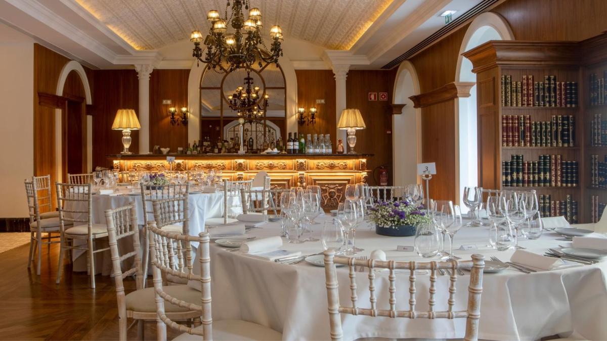 um quarto com mesas e cadeiras brancas e um lustre em InterContinental Porto - Palacio das Cardosas by IHG no Porto