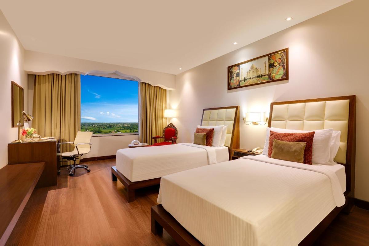 a hotel room with two beds and a window at Saura Hotel, Agra - A Club Mahindra Associate in Agra