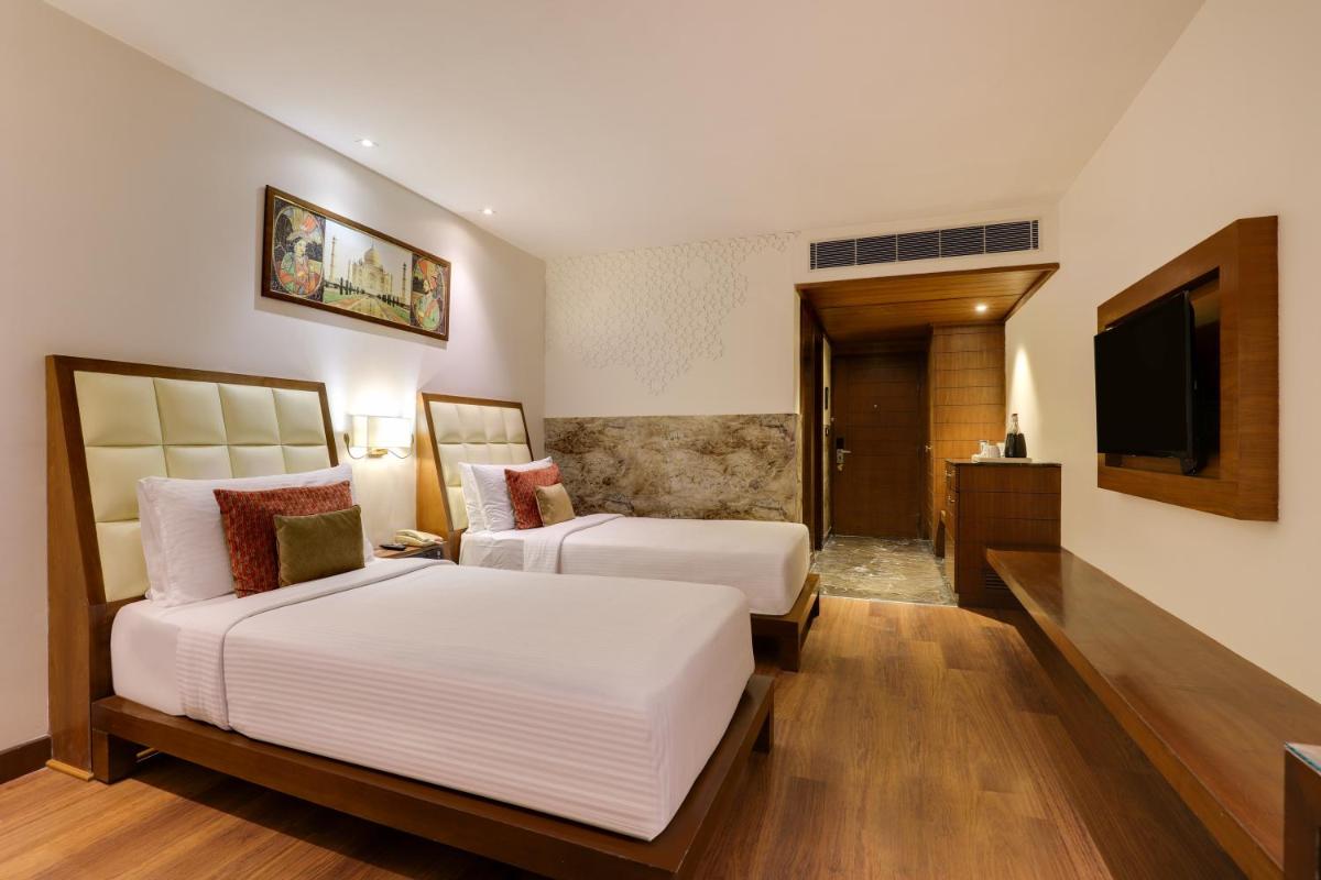 a hotel room with two beds and a television at Saura Hotel, Agra - A Club Mahindra Associate in Agra