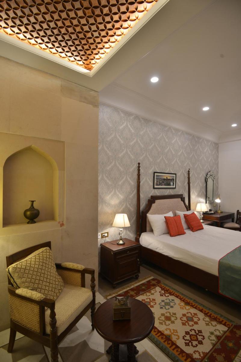 a bedroom with a bed and a chair and a table at Haveli Dharampura & Golden Haveli- UNESCO awarded Boutique Heritage Hotel in New Delhi a bedroom with a bed and a chair and a table at Haveli Dharampura & Golden Haveli- UNESCO awarded Boutique Heritage Hotel in New Delhi
