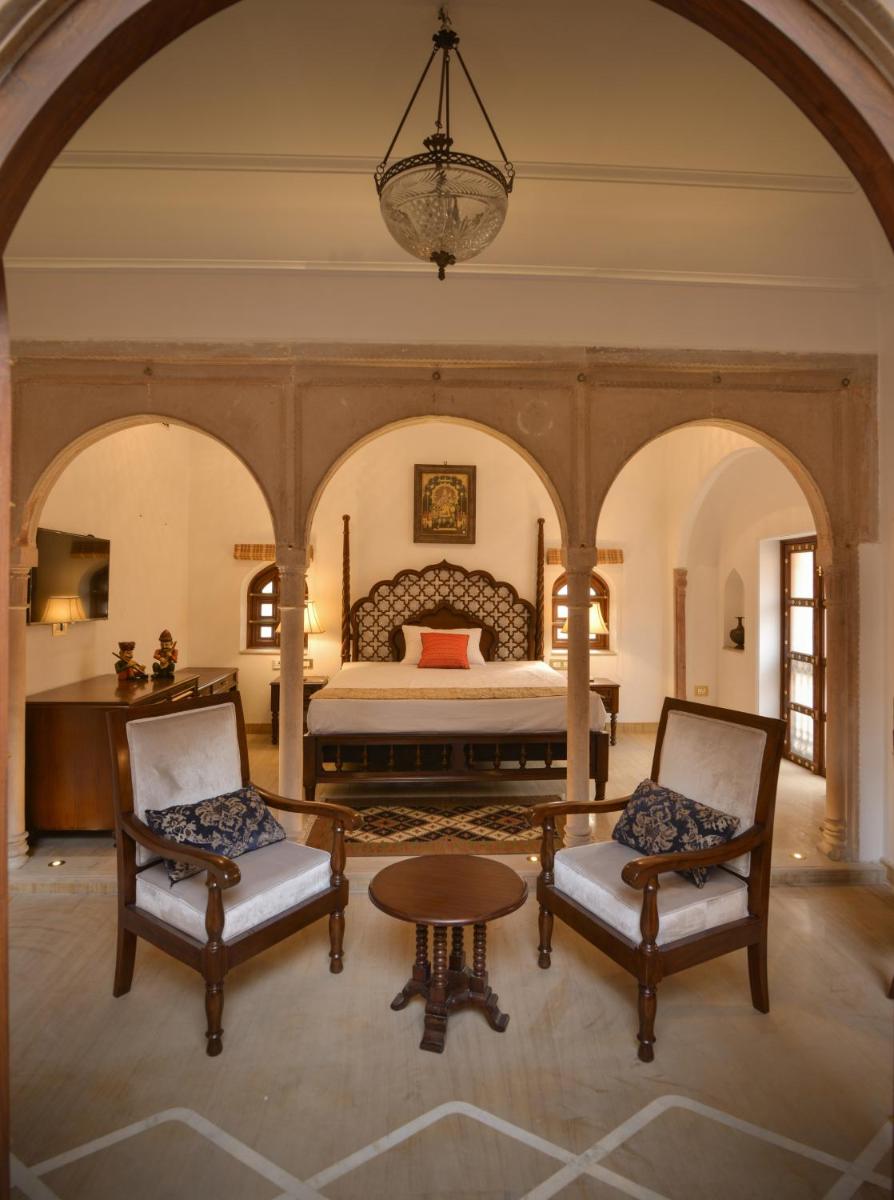a bedroom with a bed and two chairs and a table at Haveli Dharampura & Golden Haveli- UNESCO awarded Boutique Heritage Hotel in New Delhi a bedroom with a bed and two chairs and a table at Haveli Dharampura & Golden Haveli- UNESCO awarded Boutique Heritage Hotel in New Delhi