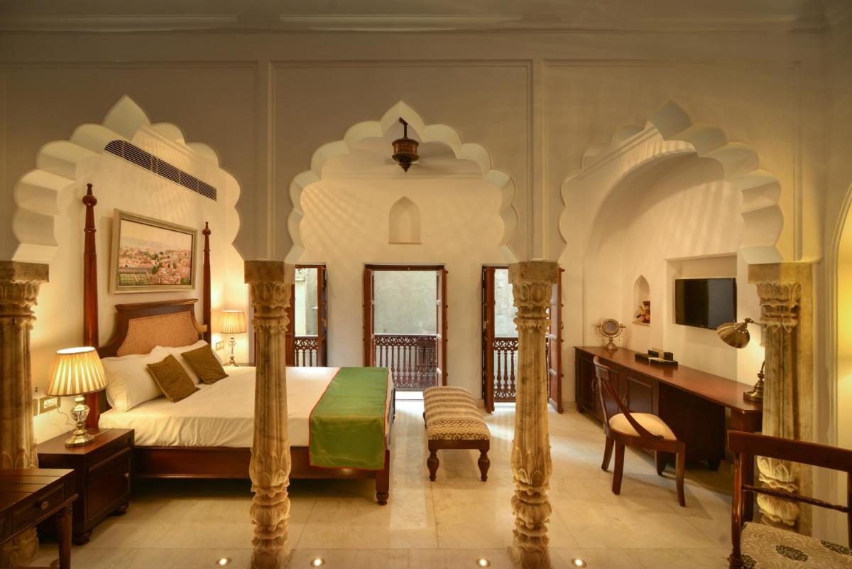 a bedroom with a bed and a desk in a room at Haveli Dharampura & Golden Haveli- UNESCO awarded Boutique Heritage Hotel in New Delhi a bedroom with a bed and a desk in a room at Haveli Dharampura & Golden Haveli- UNESCO awarded Boutique Heritage Hotel in New Delhi