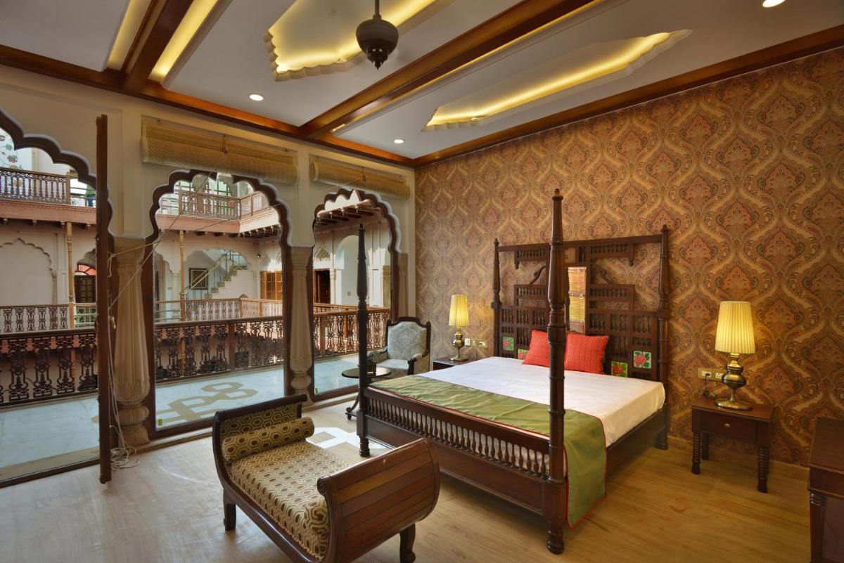 a bedroom with a bed and a chair in a room at Haveli Dharampura & Golden Haveli- UNESCO awarded Boutique Heritage Hotel in New Delhi a bedroom with a bed and a chair in a room at Haveli Dharampura & Golden Haveli- UNESCO awarded Boutique Heritage Hotel in New Delhi