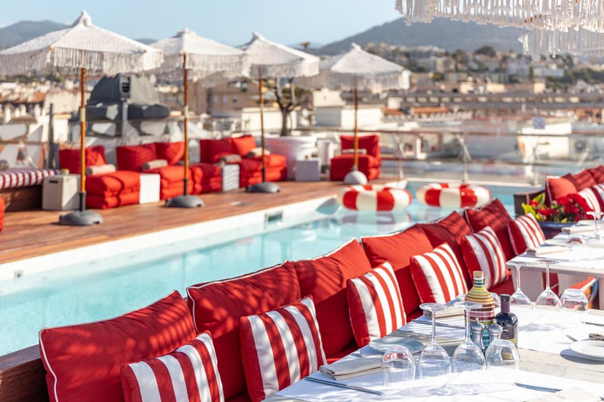 - une piscine avec des tables et des chaises rouges et blanches dans l'établissement Boscolo Nice Hotel & Spa, à Nice