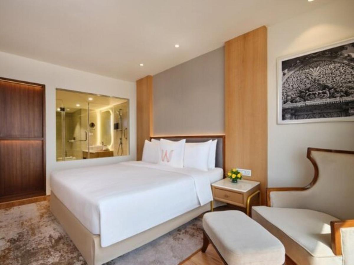 a bedroom with a large white bed and a bathroom at Welcomhotel by ITC Hotels, Ashram Road, Ahmedabad in Ahmedabad