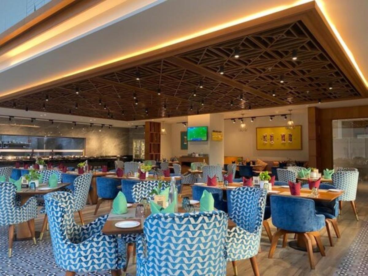 a restaurant with blue chairs and tables in a room at Welcomhotel by ITC Hotels, Ashram Road, Ahmedabad in Ahmedabad