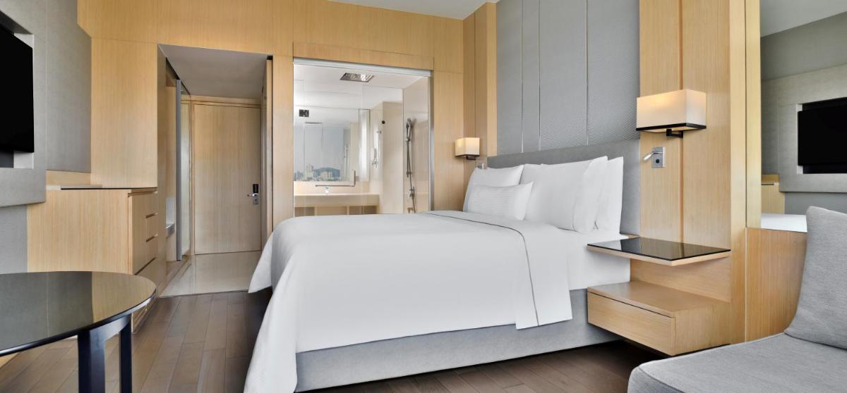 a bedroom with a large white bed and a couch at The Westin Mumbai Powai Lake in Mumbai a bedroom with a large white bed and a couch at The Westin Mumbai Powai Lake in Mumbai