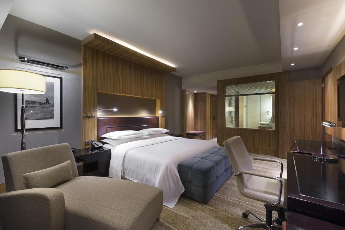 a hotel room with a bed and a desk and chairs at Sheraton Grand Bangalore Hotel at Brigade Gateway in Bengaluru