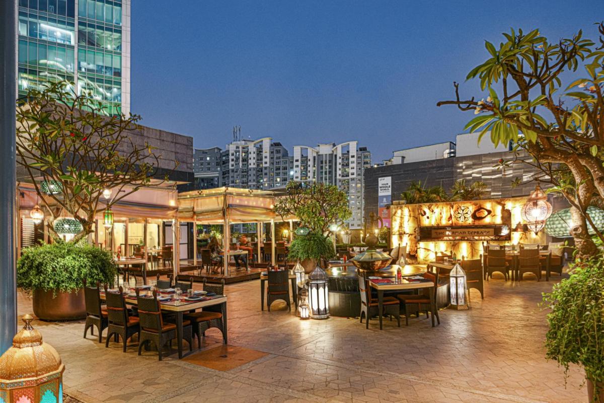 a restaurant with tables and chairs in a city at Sheraton Grand Bangalore Hotel at Brigade Gateway in Bengaluru