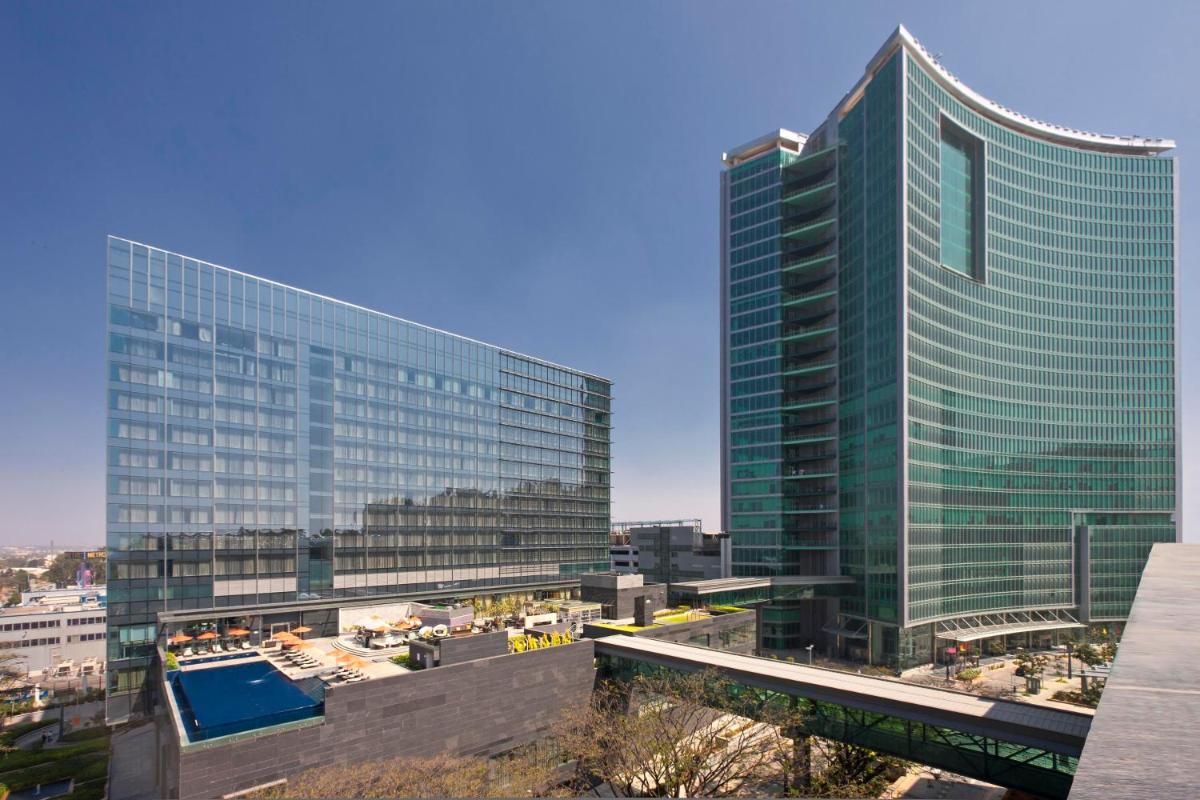 a large glass building with a pool in front of it at Sheraton Grand Bangalore Hotel at Brigade Gateway in Bengaluru