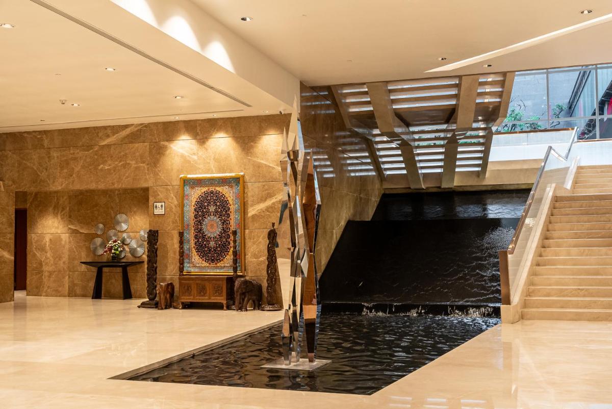 a lobby with a pond in the middle of a building at Sheraton Grand Bangalore Hotel at Brigade Gateway in Bengaluru