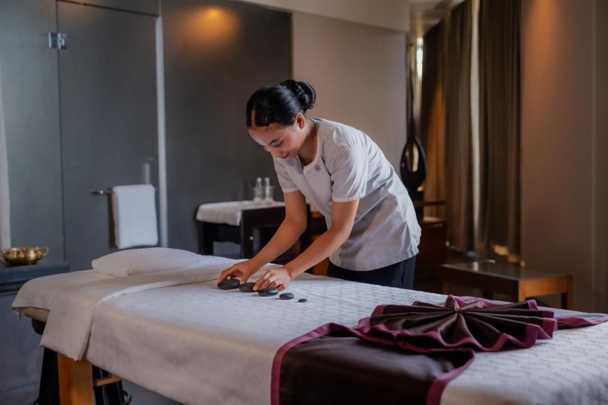 a woman is working on a bed in a hotel room at Sheraton Grand Bangalore Hotel at Brigade Gateway in Bengaluru