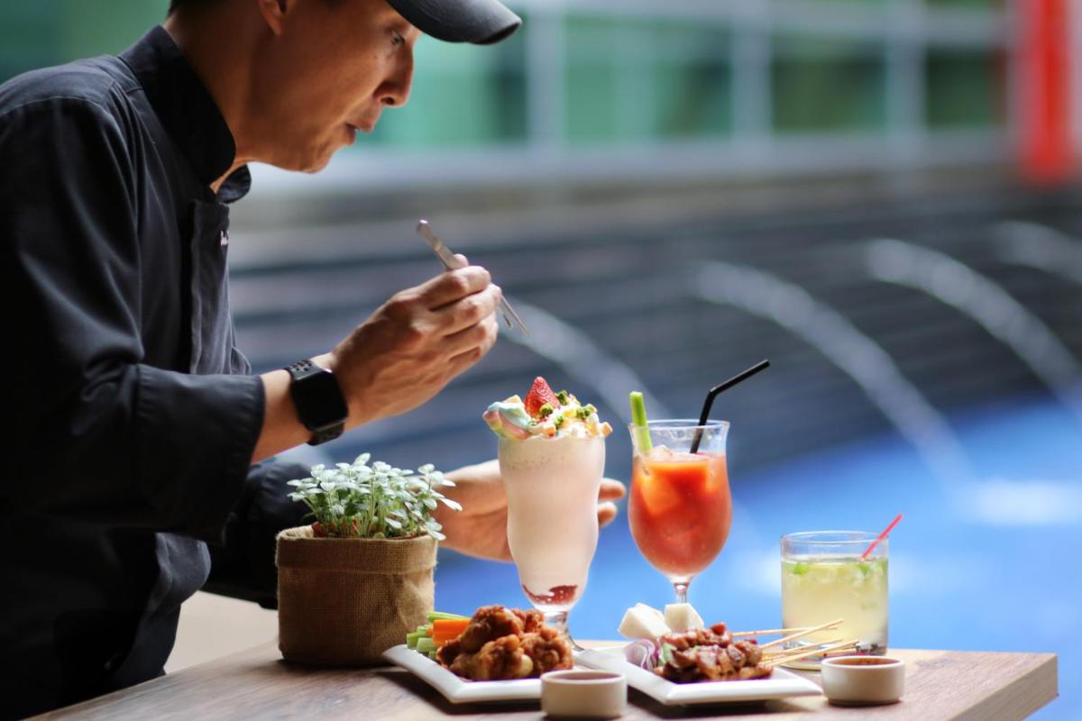 a man sitting at a table with food and drinks at Royal Plaza on Scotts in Singapore