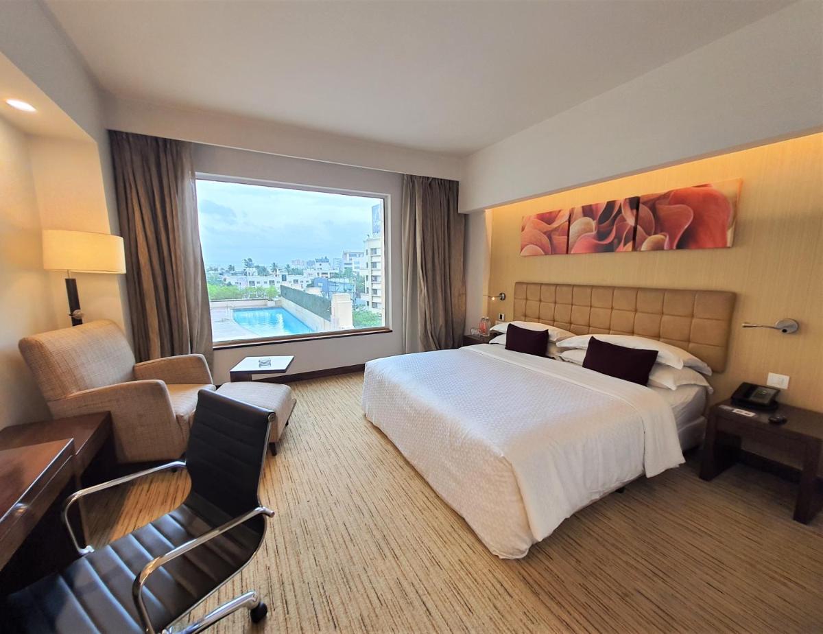 a hotel room with a large bed and a large window at Four Points by Sheraton Hotel and Serviced Apartments Pune in Pune