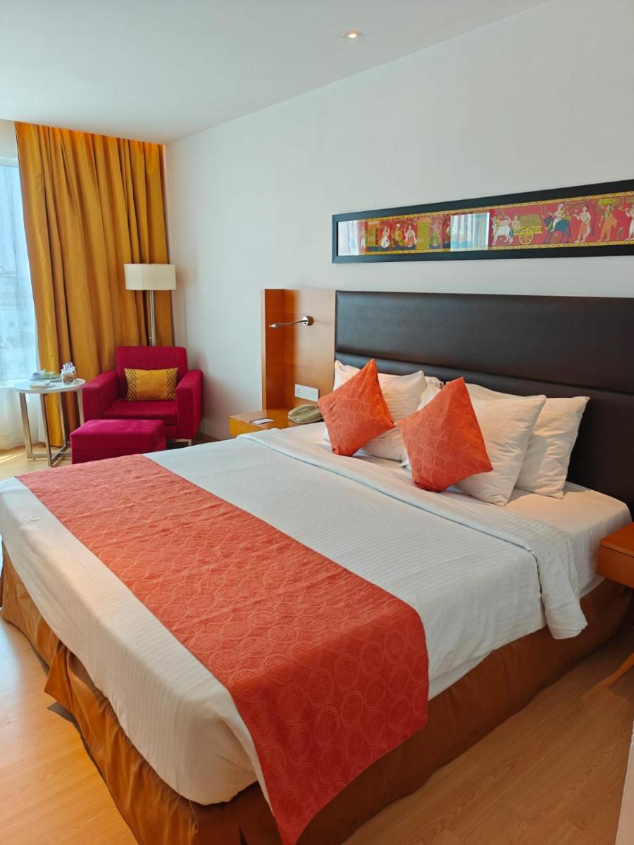 a bedroom with a large bed with orange and white pillows at Mercure Hyderabad KCP Banjara Hills, An Accor Hotel in Hyderabad