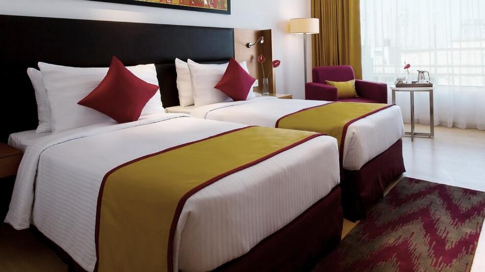 a hotel room with two beds with red pillows at Mercure Hyderabad KCP Banjara Hills, An Accor Hotel in Hyderabad