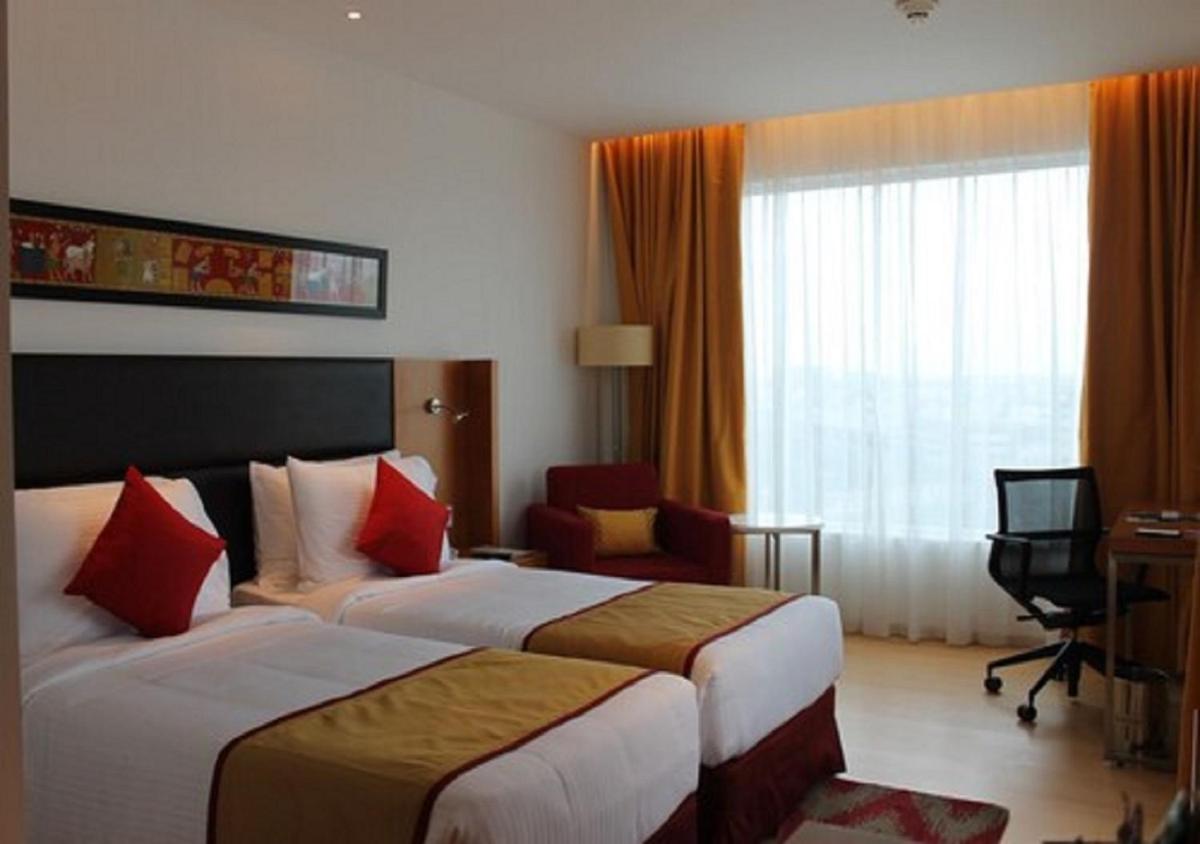a hotel room with two beds and a television at Mercure Hyderabad KCP Banjara Hills, An Accor Hotel in Hyderabad
