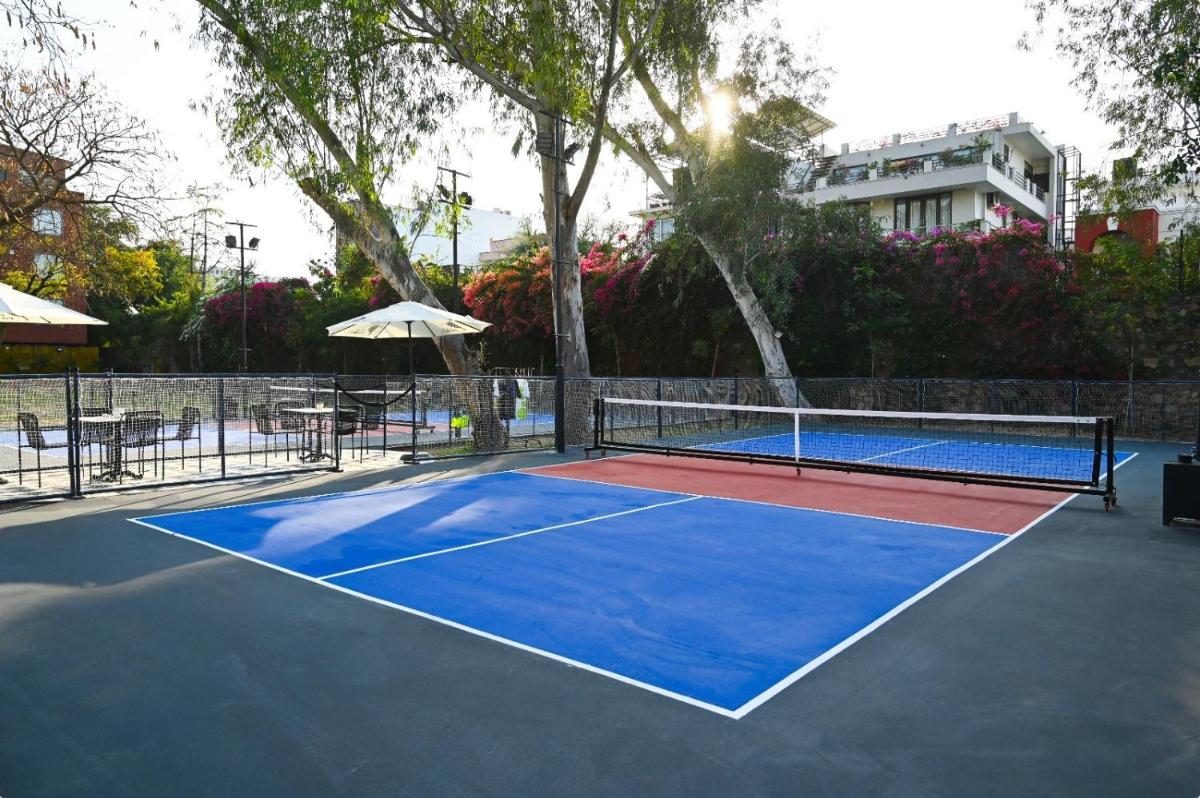 a tennis court with a blue tennis court at Brij Nest, Jaipur - An All Suite Boutique Hotel in Jaipur