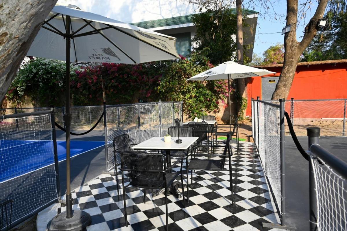 a table and chairs with an umbrella on a tennis court at Brij Nest, Jaipur - An All Suite Boutique Hotel in Jaipur