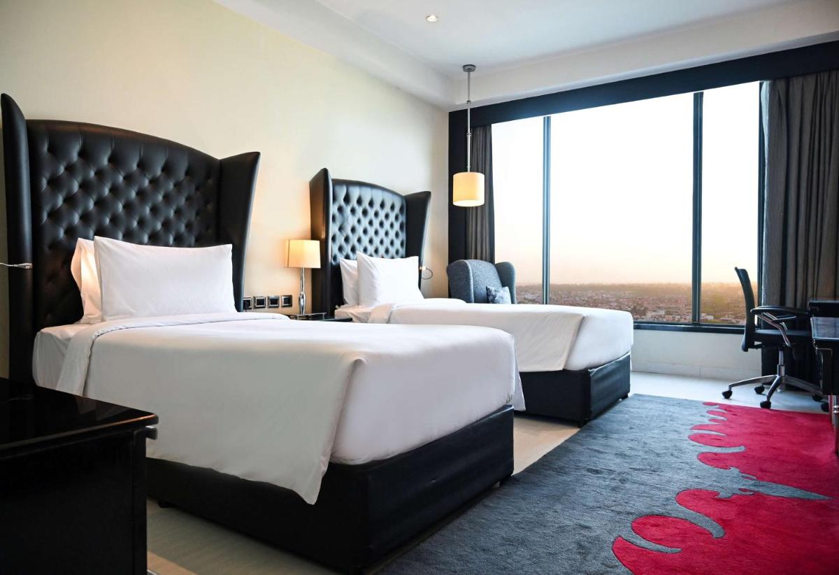 a hotel room with two beds and a large window at Radisson Blu Hotel New Delhi Paschim Vihar in New Delhi a hotel room with two beds and a large window at Radisson Blu Hotel New Delhi Paschim Vihar in New Delhi