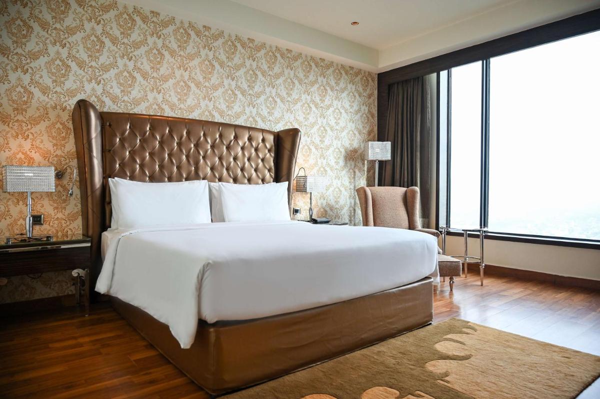 a bedroom with a large bed and a large window at Radisson Blu Hotel New Delhi Paschim Vihar in New Delhi a bedroom with a large bed and a large window at Radisson Blu Hotel New Delhi Paschim Vihar in New Delhi