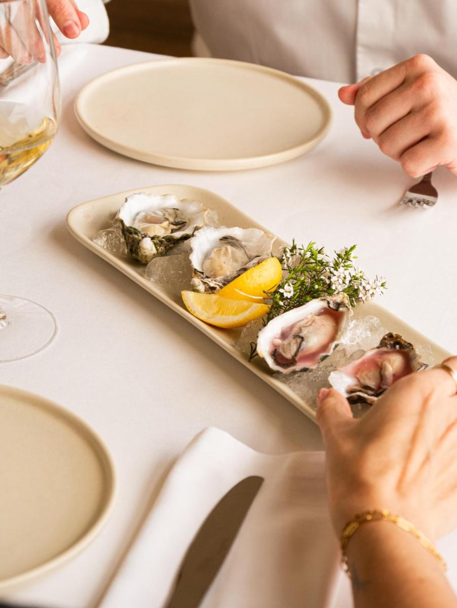 Una bandeja de ostras en una mesa con un plato de comida. en Hostal Empúries, en L'Escala