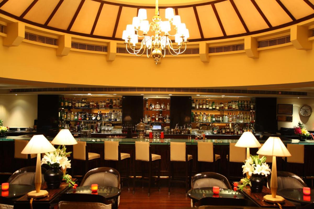 a restaurant with a bar with chairs and a chandelier at Taj Mahal, New Delhi in New Delhi