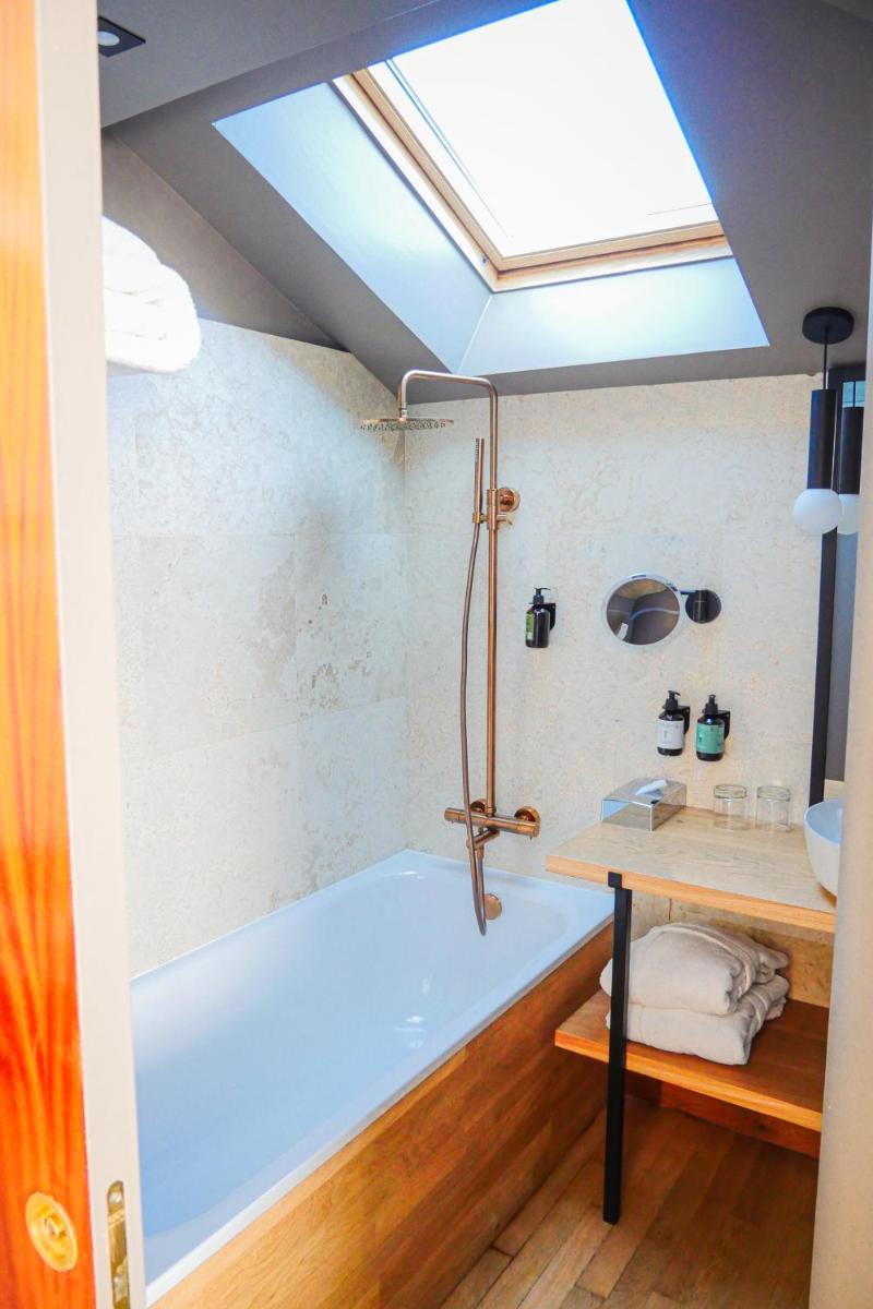 La salle de bains est pourvue d'une baignoire bleue et d'une lucarne. dans l'établissement Villa Kerasy Hotel Spa, à Vannes