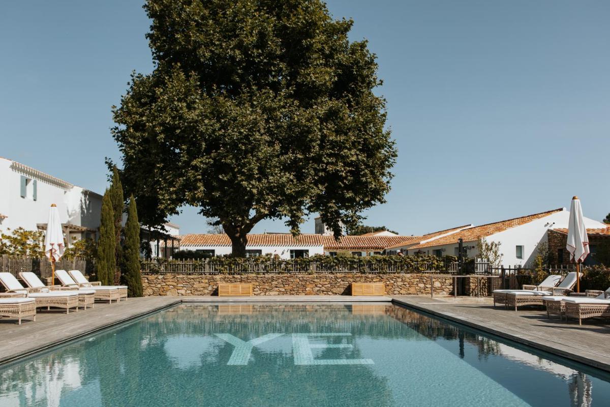 - une piscine avec des chaises longues et un arbre dans l'établissement La Mission Hôtel & SPA - l'île d'Yeu, à L'Ile d'Yeu