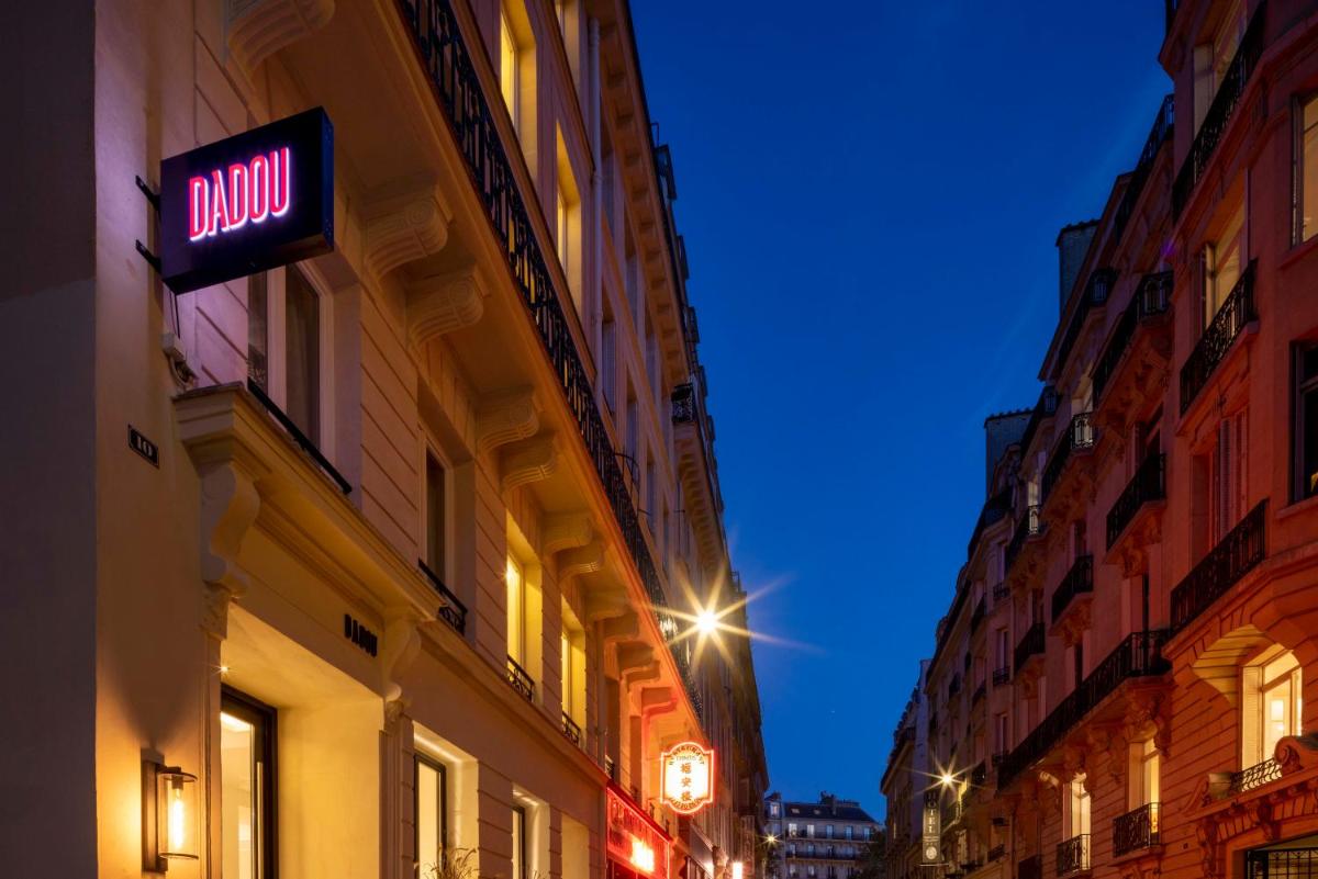 un panneau néon sur le côté d'un bâtiment la nuit dans l'établissement Dadou Paris, à Paris