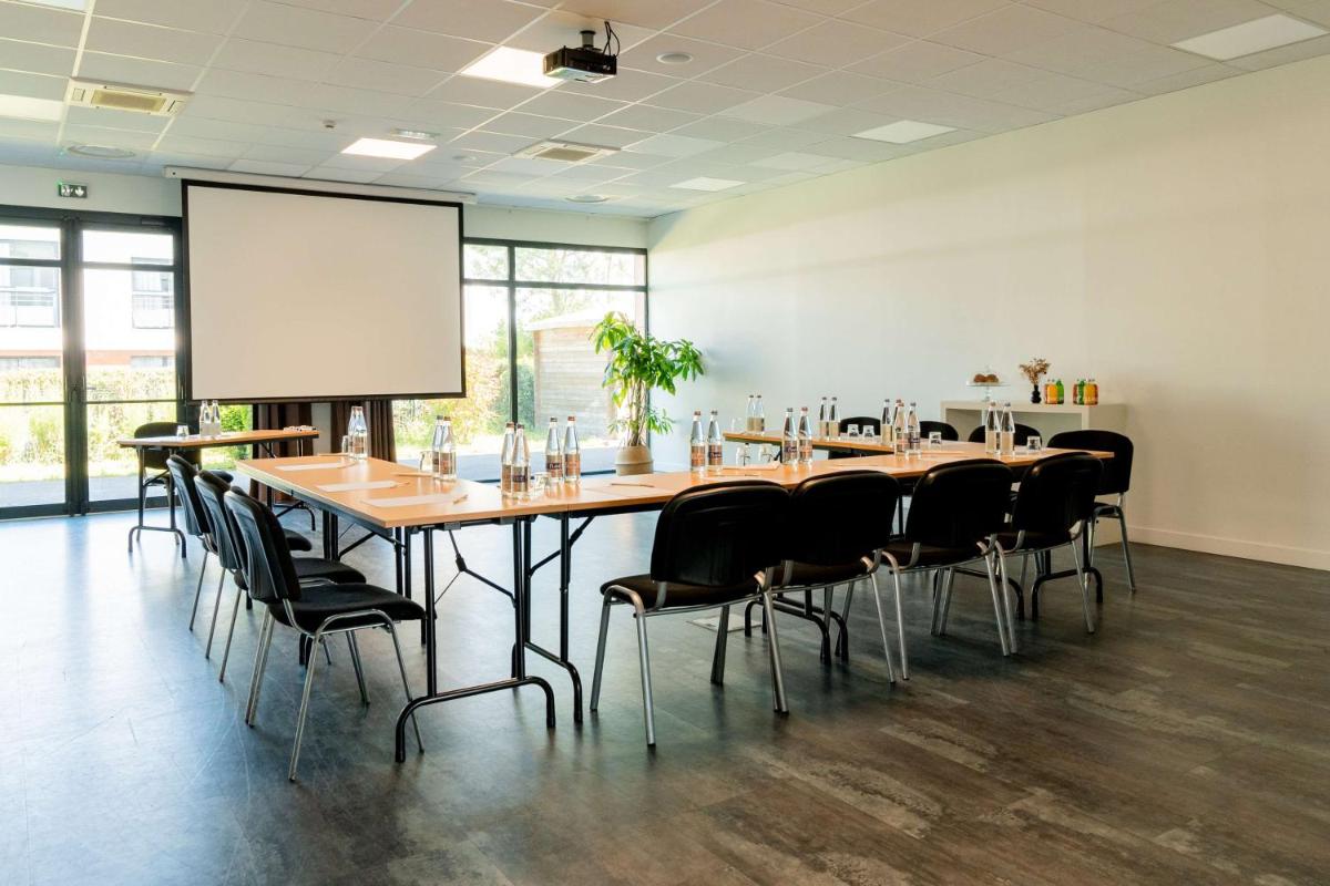 une grande salle de conférence avec une grande table et des chaises dans l'établissement Best Western Hôtel De La Cité & Spa, à Guérande 27 autres photos