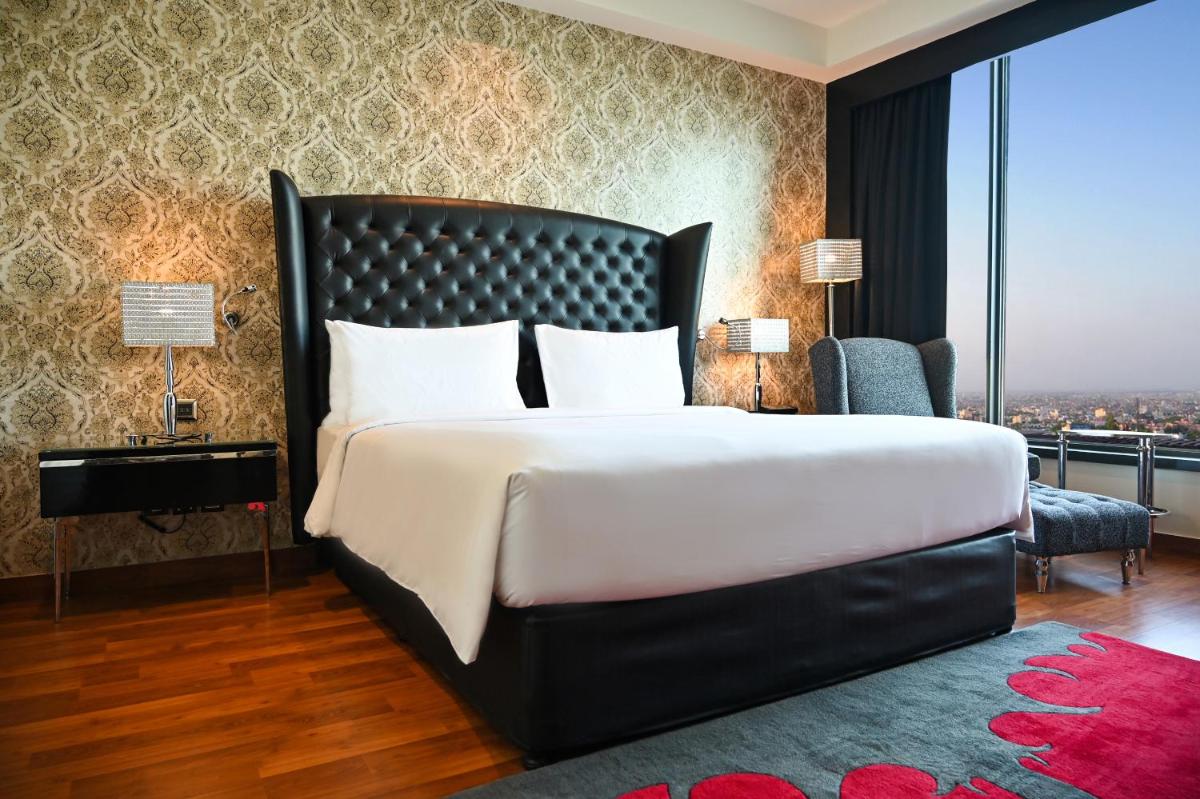 a bedroom with a large bed and a large window at Radisson Blu Hotel New Delhi Paschim Vihar in New Delhi a bedroom with a large bed and a large window at Radisson Blu Hotel New Delhi Paschim Vihar in New Delhi