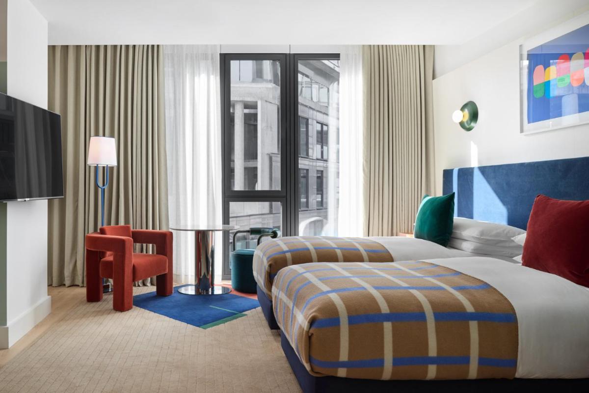 ein Hotelzimmer mit zwei Betten und einem Stuhl in der Unterkunft Kimpton Main Frankfurt by IHG in Frankfurt am Main