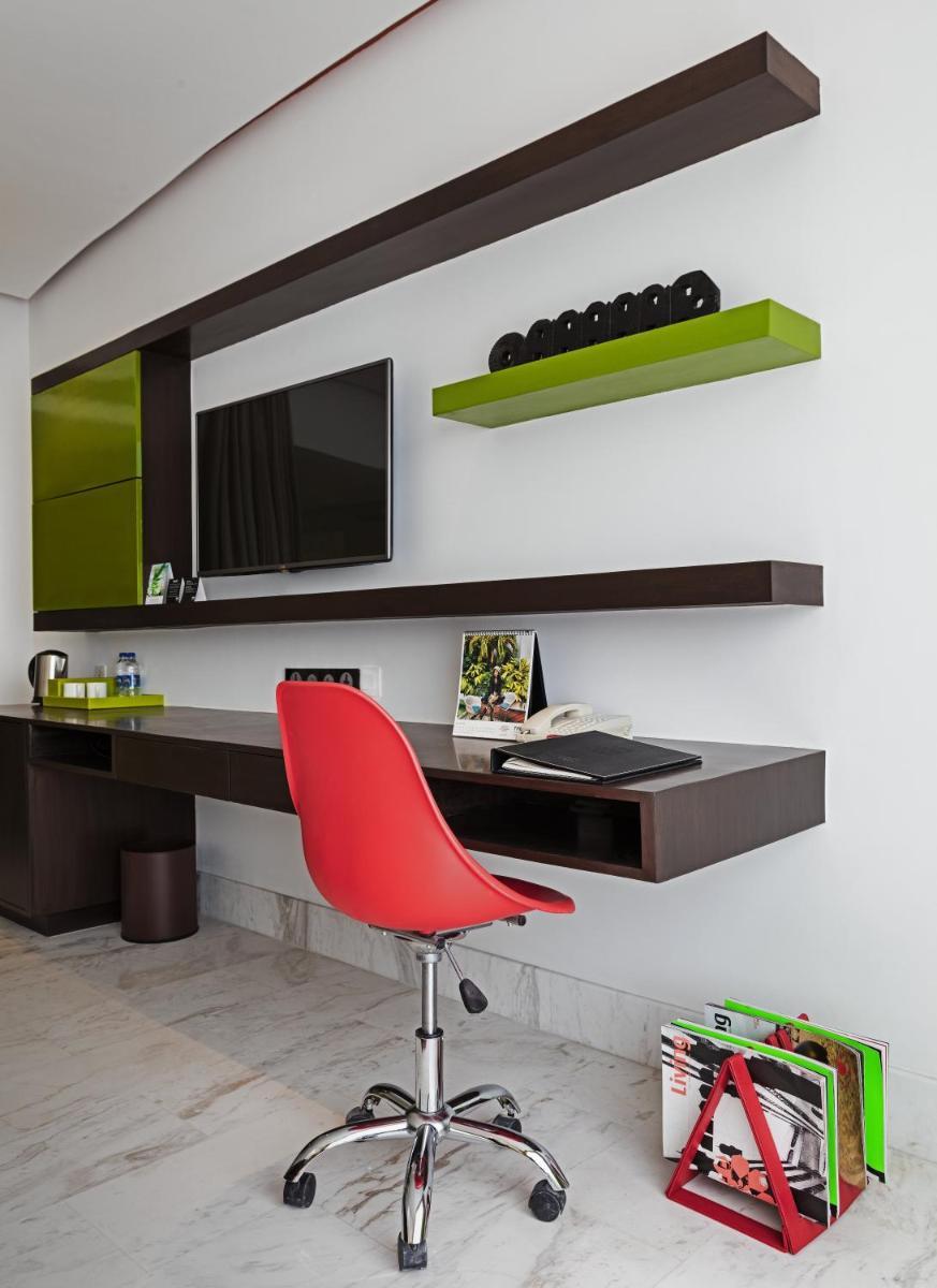 a red chair in front of a desk with a television at The Park Chennai in Chennai a red chair in front of a desk with a television at The Park Chennai in Chennai
