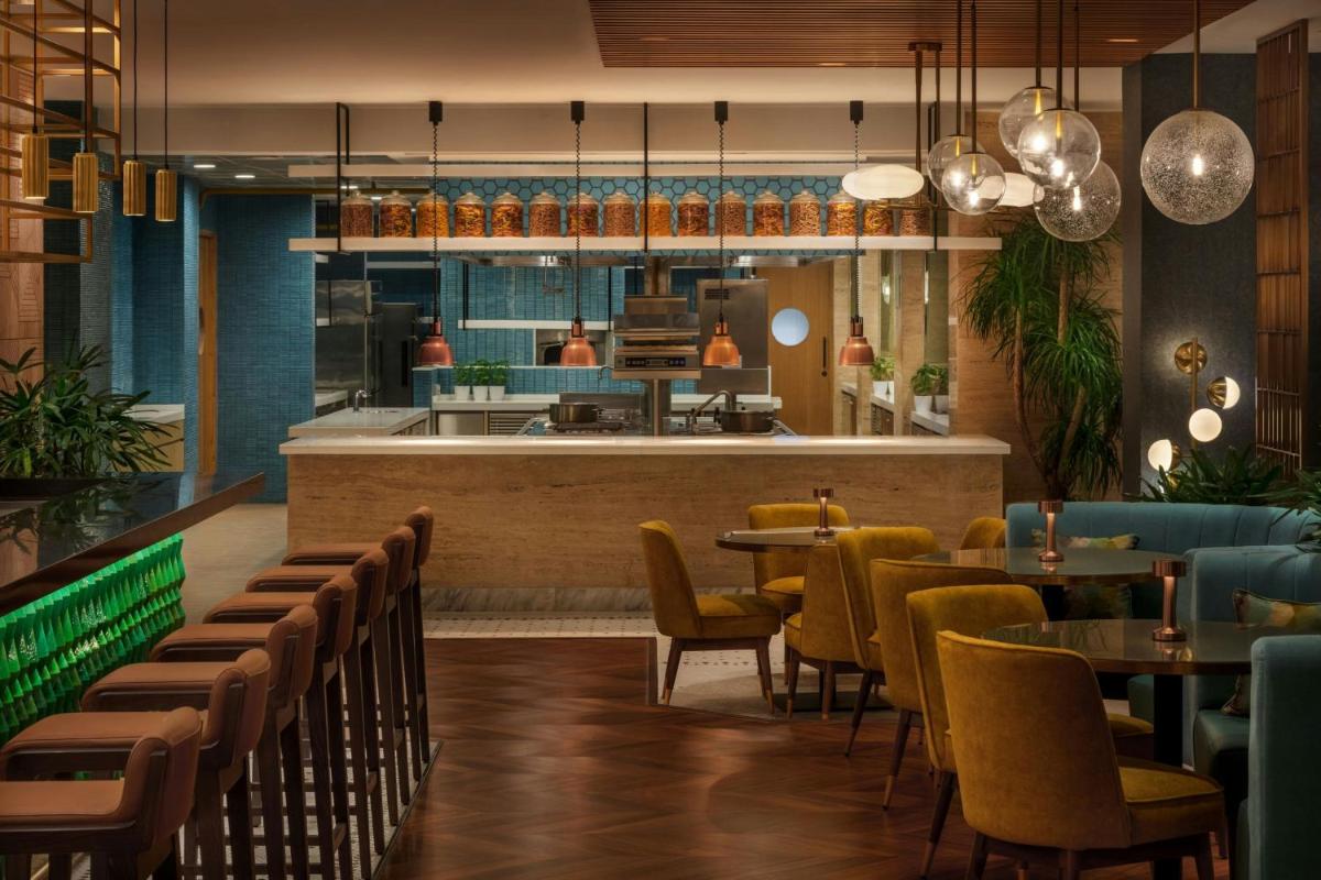 a restaurant with tables and chairs and a kitchen at JW Marriott Mumbai Juhu in Mumbai