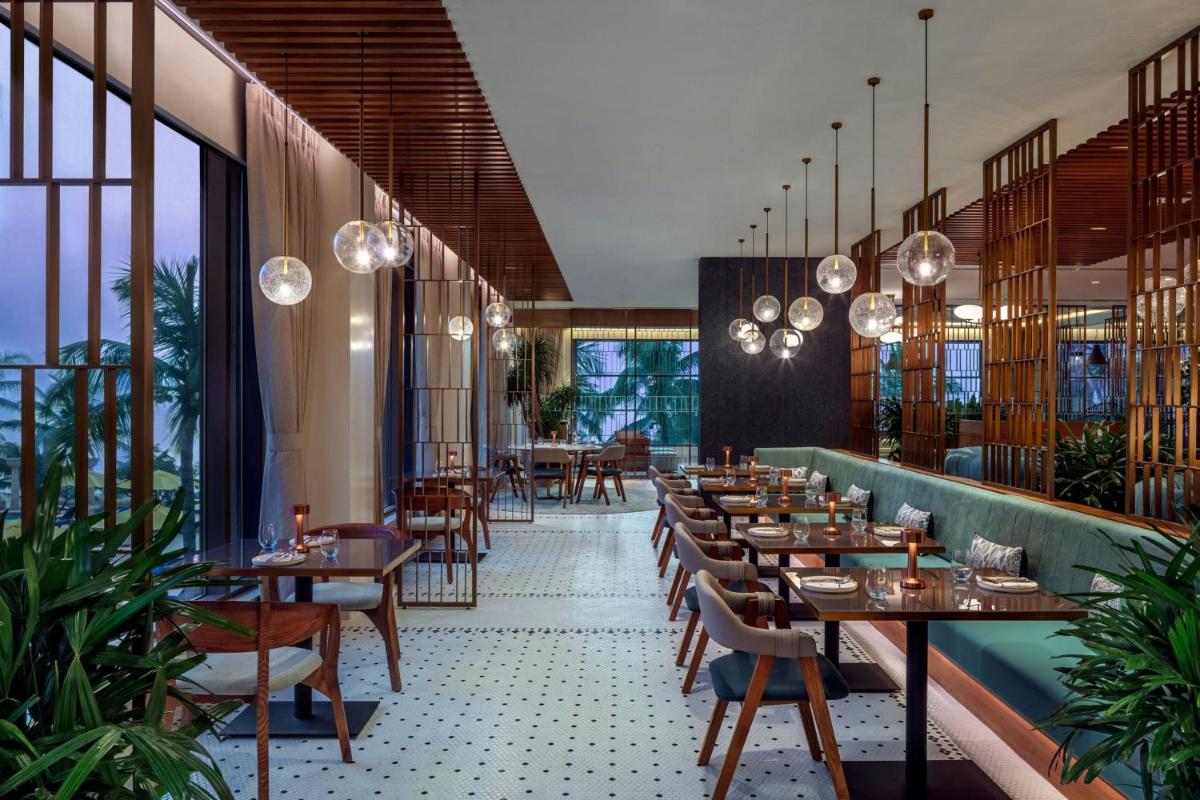 a restaurant with wooden tables and chairs and windows at JW Marriott Mumbai Juhu in Mumbai