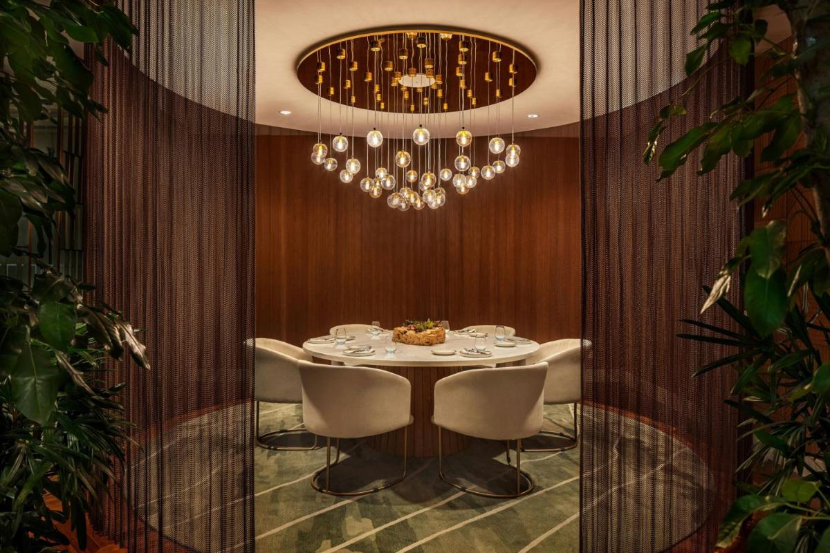 a dining room with a table and a chandelier at JW Marriott Mumbai Juhu in Mumbai