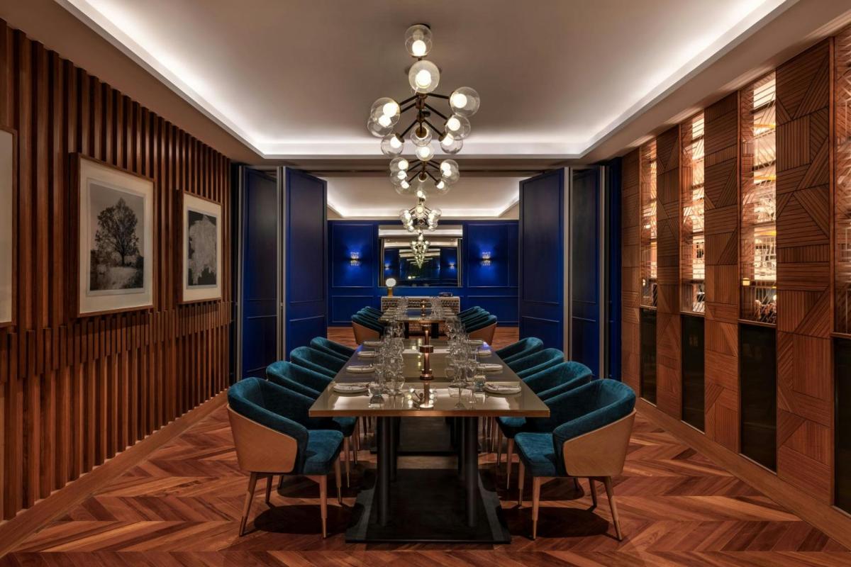 a dining room with a long table and blue chairs at JW Marriott Mumbai Juhu in Mumbai