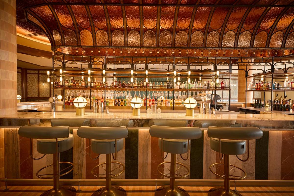 un bar con taburetes frente a un bar en SLS Barcelona, en Barcelona
