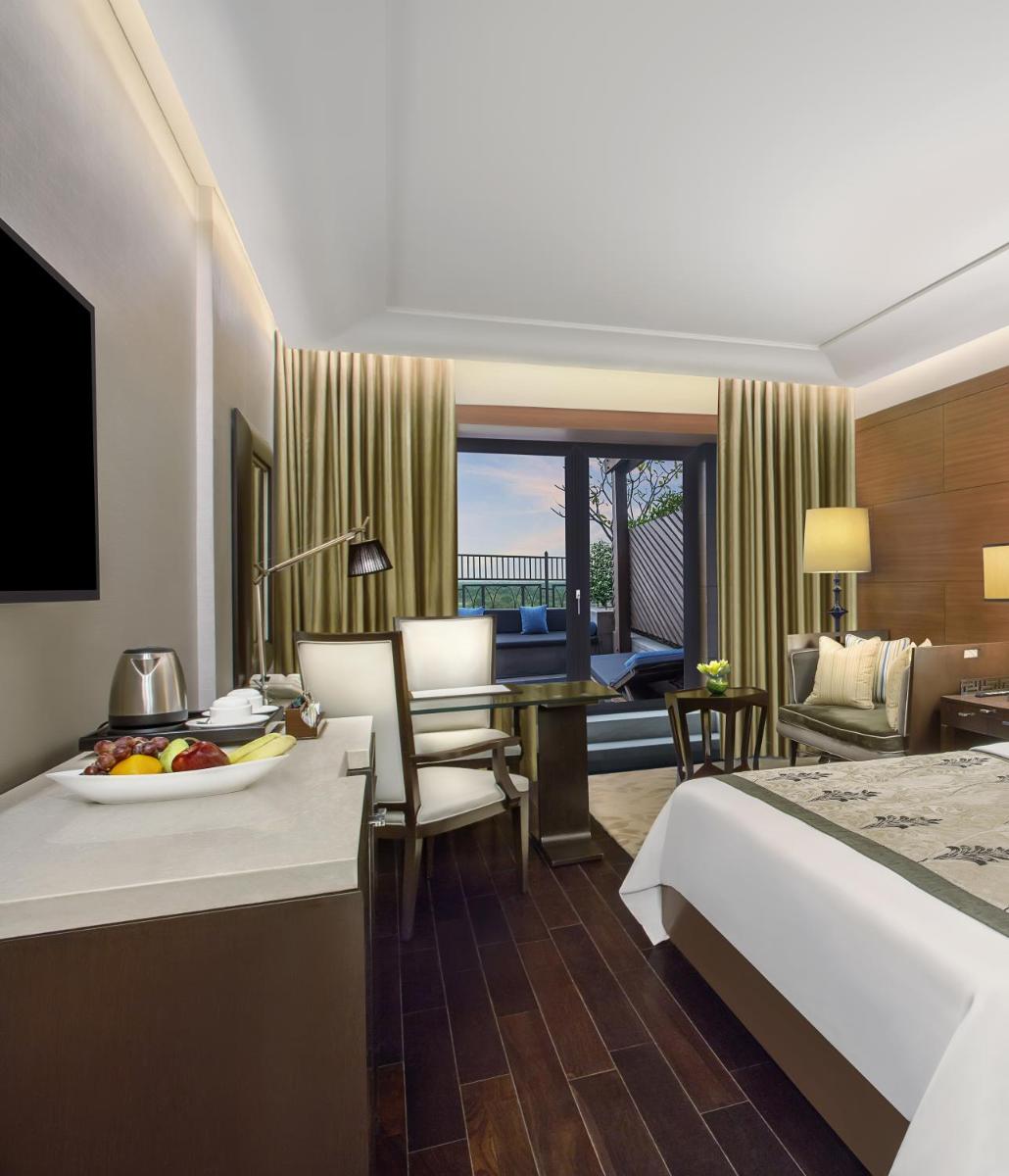 a hotel room with a bed and a desk with a plate of fruit at The Leela Ambience Gurugram Hotel & Residences - The Luxury Urban Sanctuary in Gurgaon