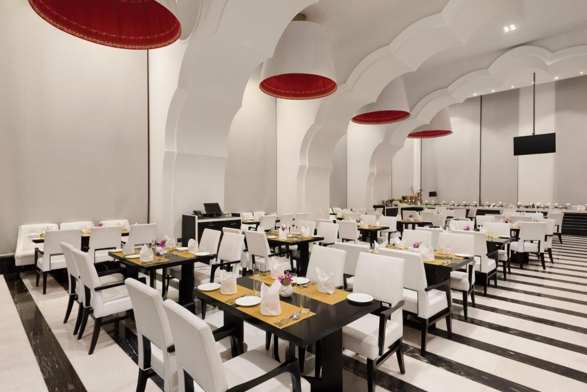 a dining room with tables and white chairs at Saura Hotel, Agra - A Club Mahindra Associate in Agra