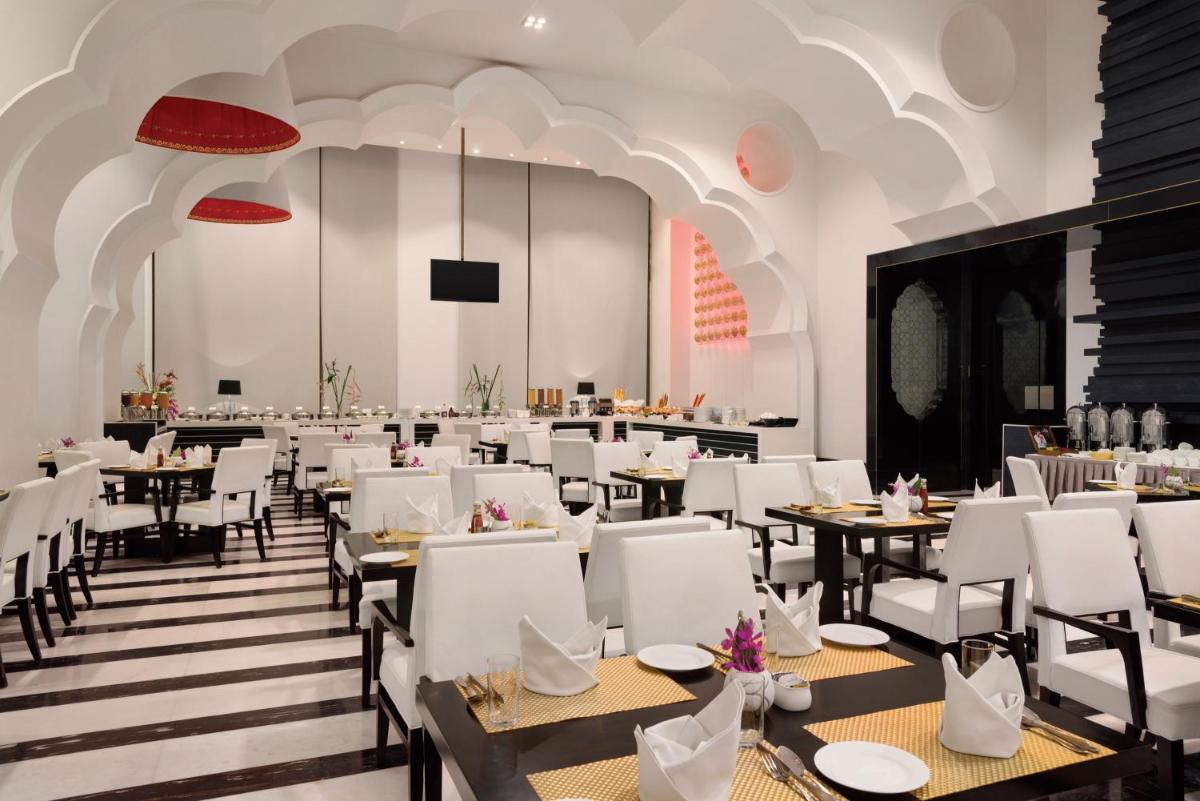 a dining room with tables and white chairs at Saura Hotel, Agra - A Club Mahindra Associate in Agra